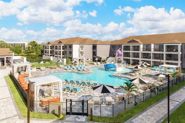 Ein Hotel mit Schwimmbad, Liegestühlen und einem eingezäunten Bereich.