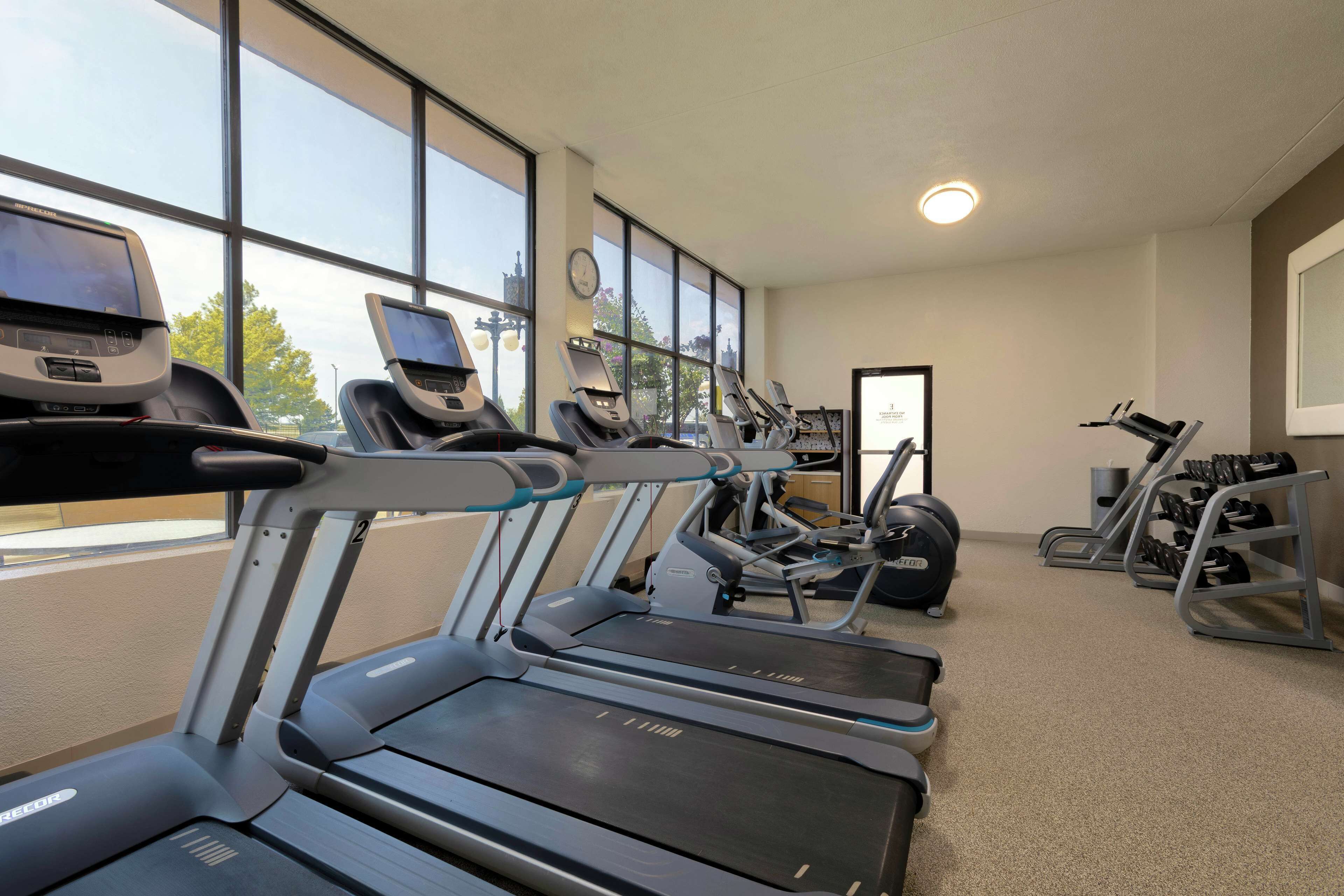Un gimnasio con cintas de correr, máquinas de pesas y mancuernas.