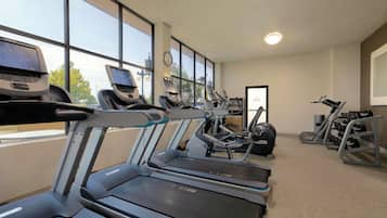 Un gimnasio con cintas de correr, máquinas de pesas y mancuernas.