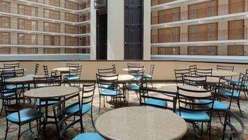 A multi-level atrium with round tables and chairs, featuring a patterned carpet and wooden balconies.