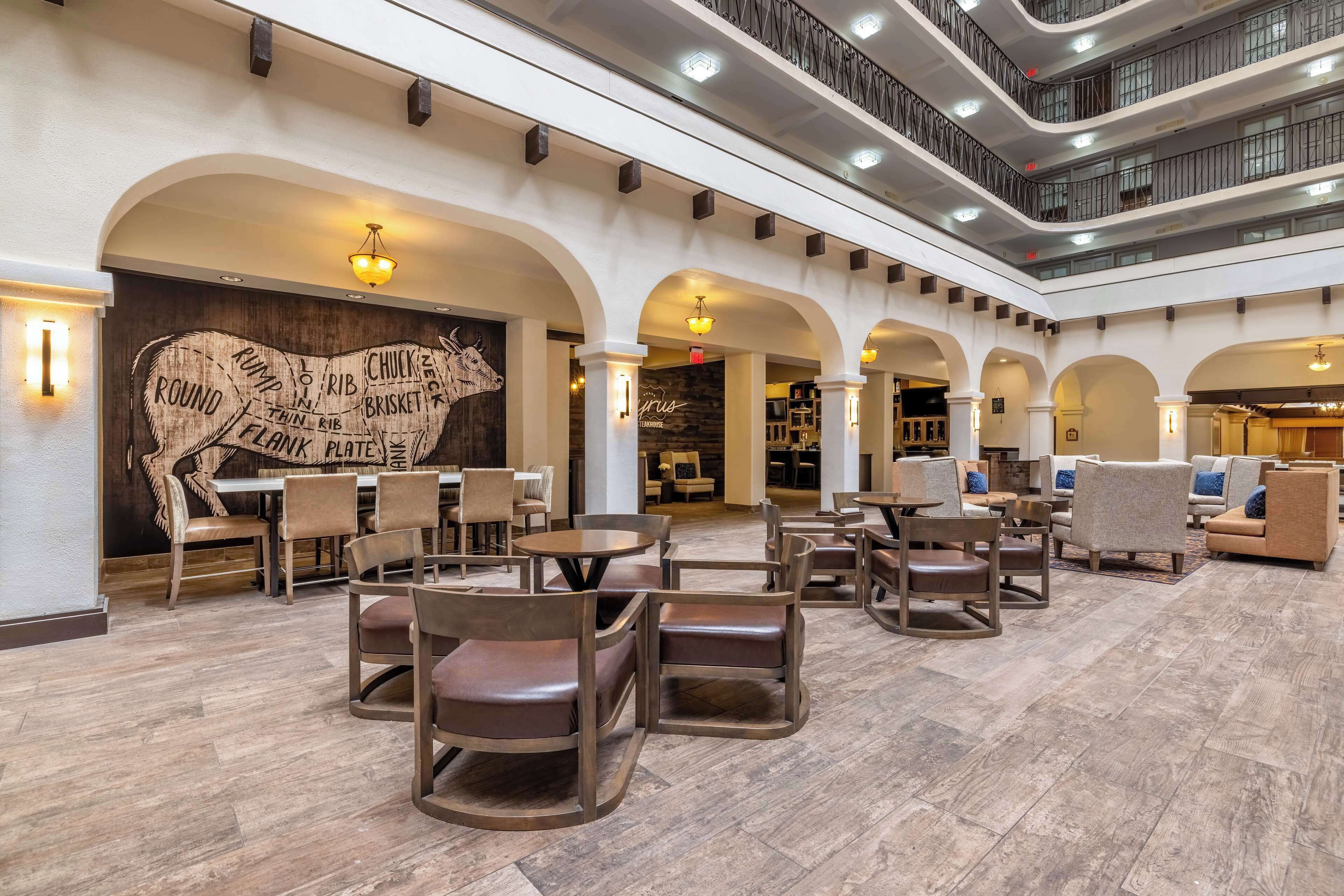 A spacious lobby with multiple seating areas, a large wall mural, and a multi-level balcony.