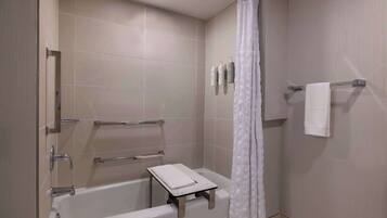 A modern bathroom with a bathtub, a shower curtain, a towel rack, and a small table with a towel.