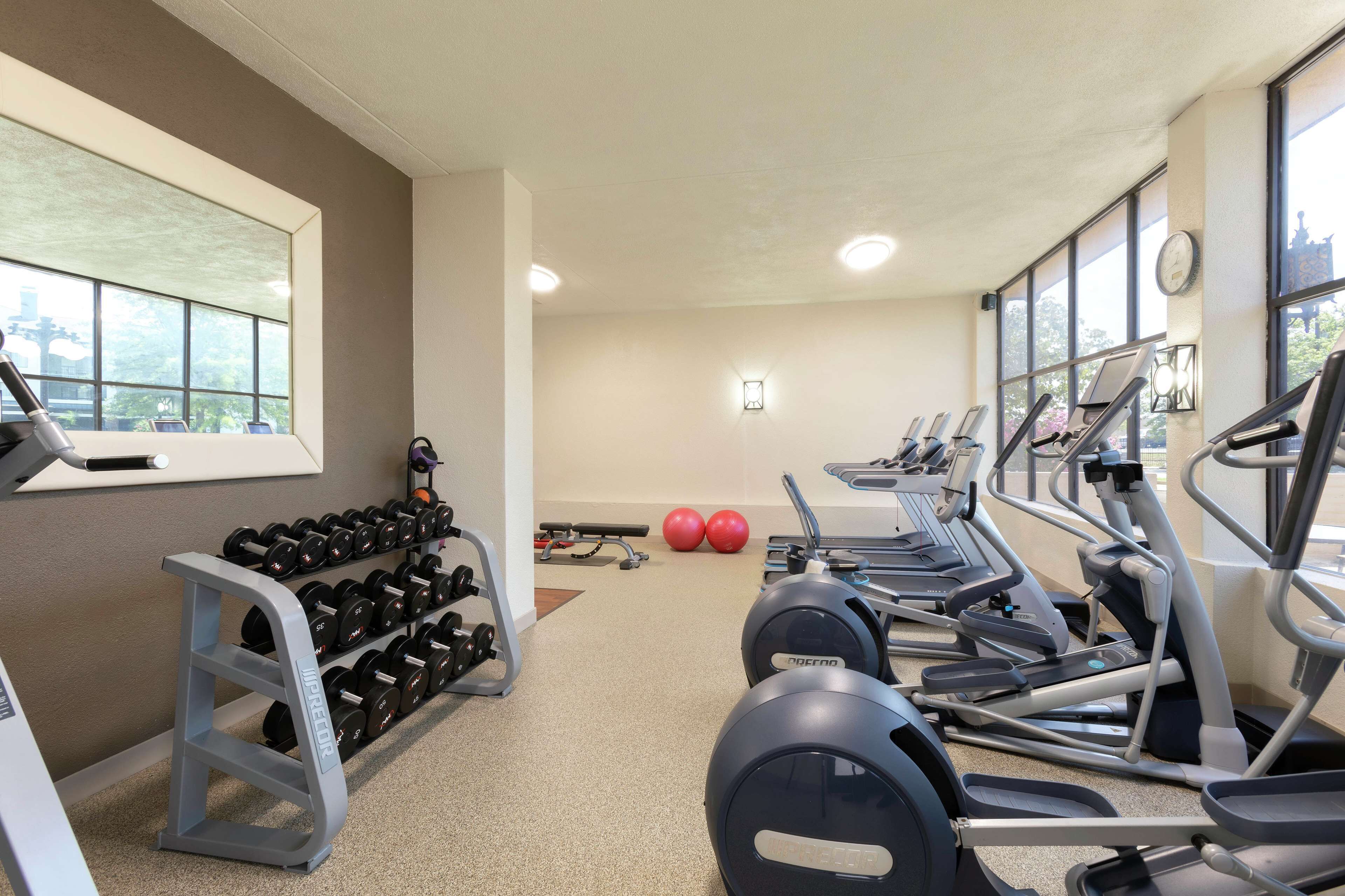 Un gimnasio con cintas de correr, mancuernas y pelotas de ejercicio.