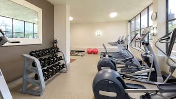 Un gimnasio con cintas de correr, mancuernas y pelotas de ejercicio.