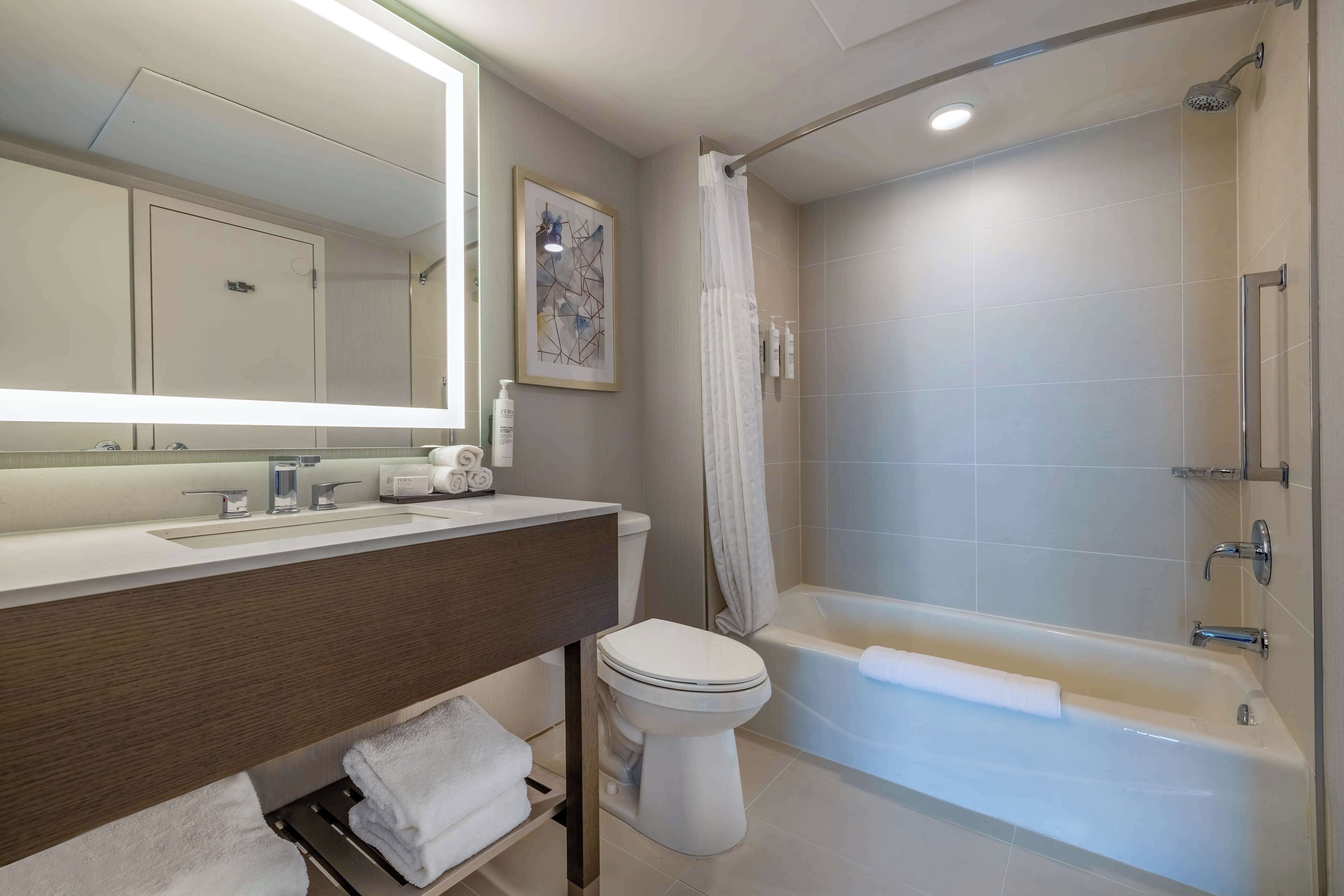 Ein modernes Badezimmer mit Waschbecken, Spiegel, Toilette und Badewanne.
