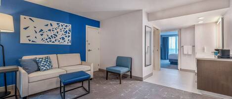 A modern living room with a blue accent wall, a sofa, a chair, and a small table.