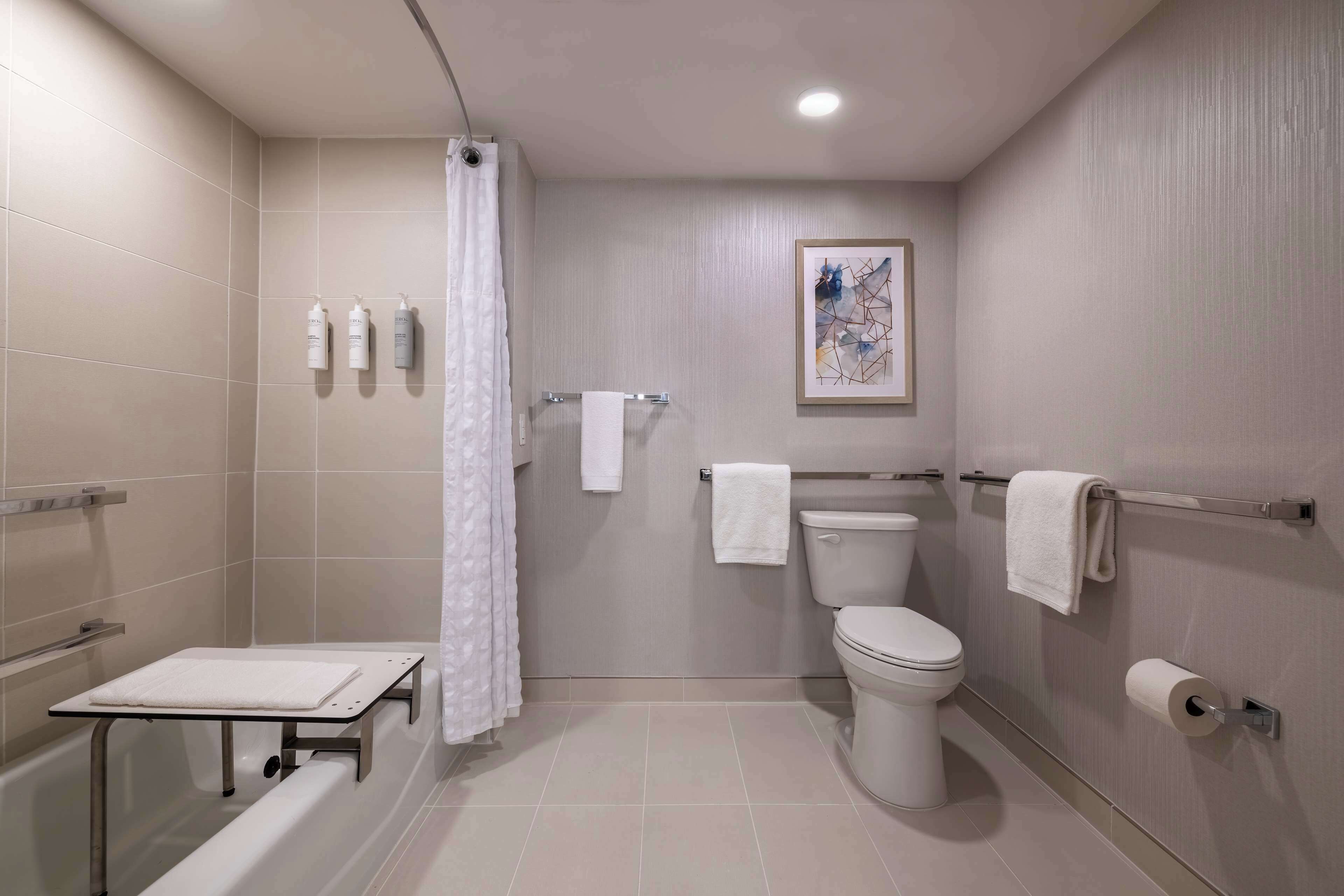 A modern bathroom with a bathtub, toilet, and shower curtain.