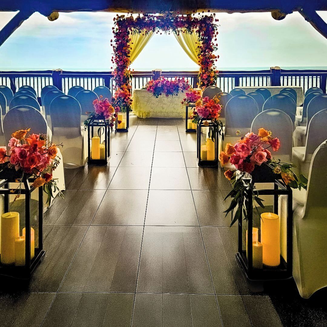 An outdoor ceremony aisle with chairs and floral arrangements.