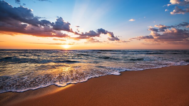 Una playa con olas al atardecer.
