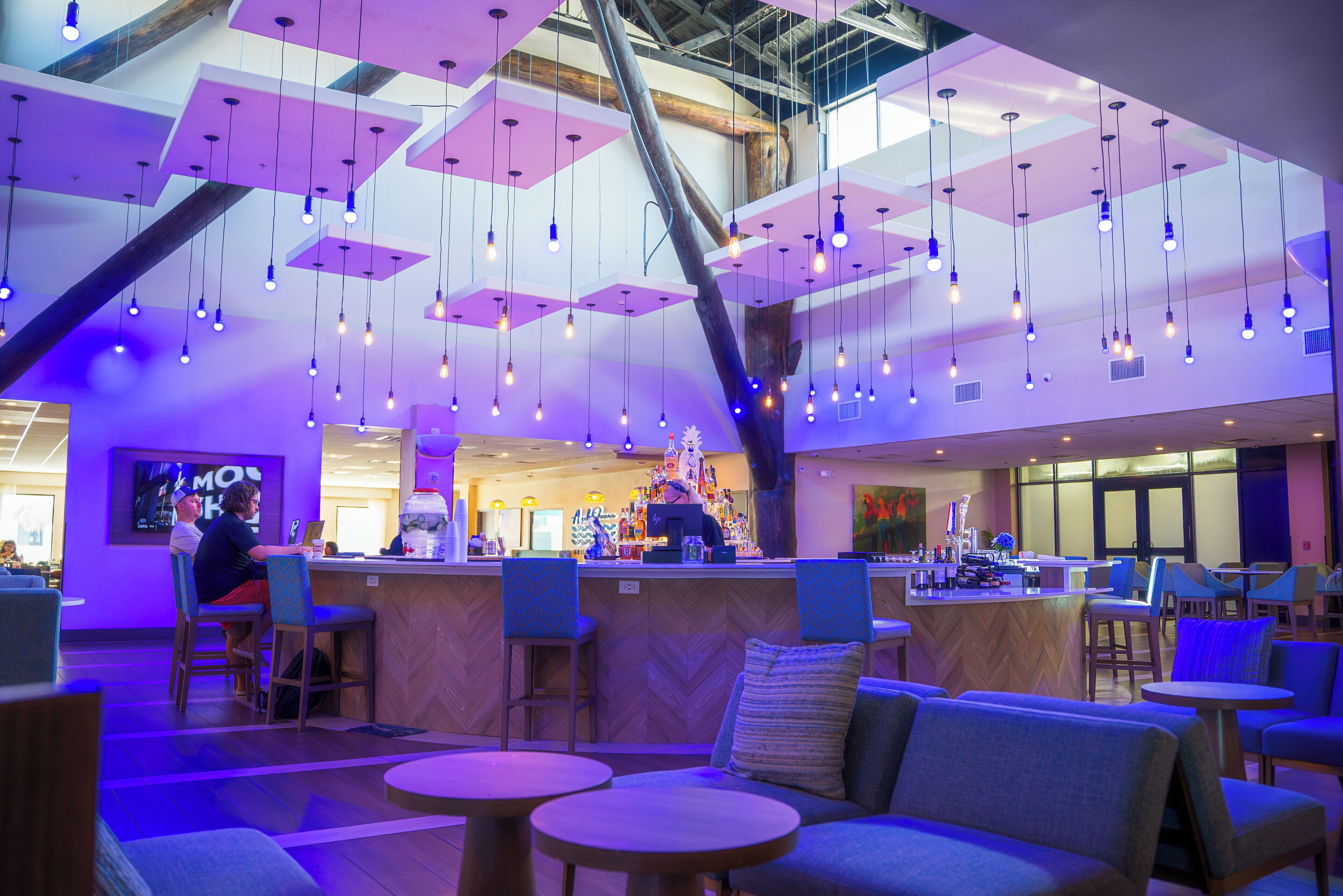 A modern bar area with hanging lights, seating, and a bar counter.