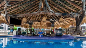 Un área de piscina con bar, vigas de madera y techo de paja.