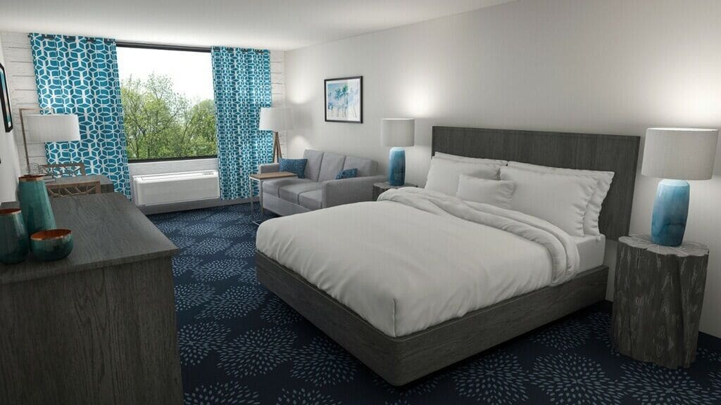 Una habitación de hotel moderna con una cama grande, una zona de estar con sofá, un escritorio y un ventanal con cortinas estampadas.