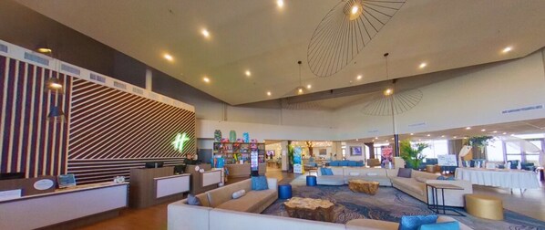 A spacious lobby with a reception desk, seating areas, and a modern ceiling design. - Holiday Inn Resort South Padre Island - Beach Front by IHG (South Padre Island)
