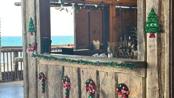 Una zona de bar rústica de madera con vista al océano, decorada con adornos navideños.