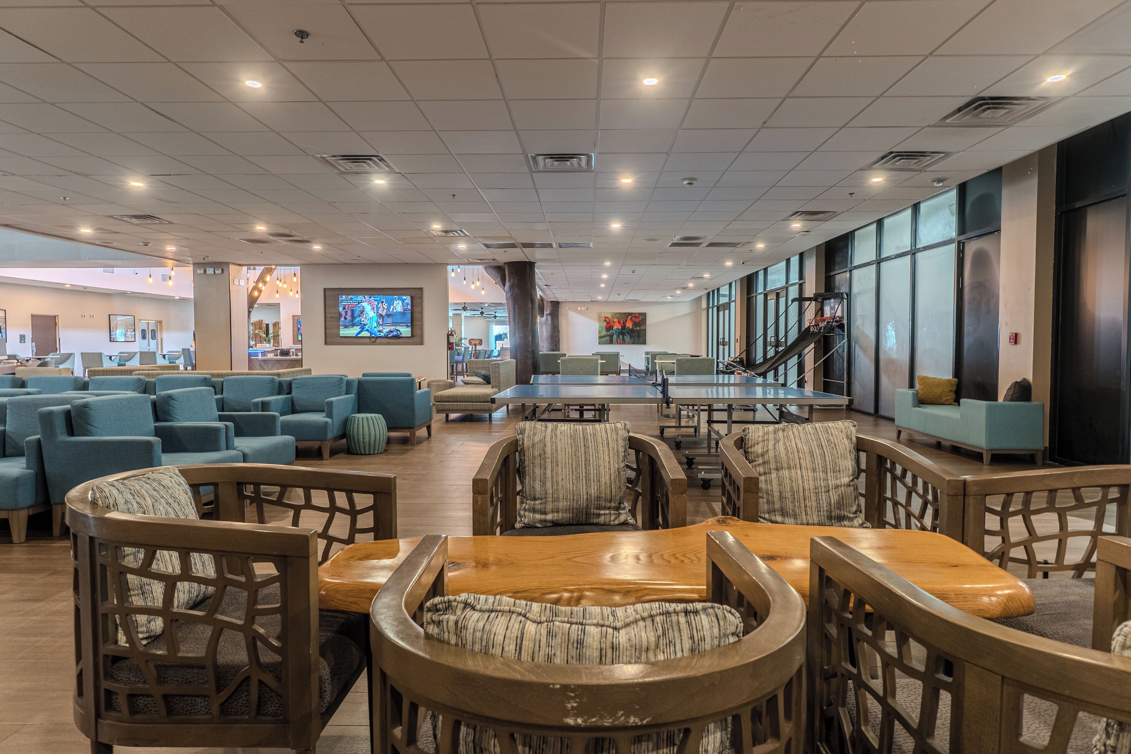 A spacious lobby with multiple seating areas, including sofas and wooden chairs, and a large table in the center.