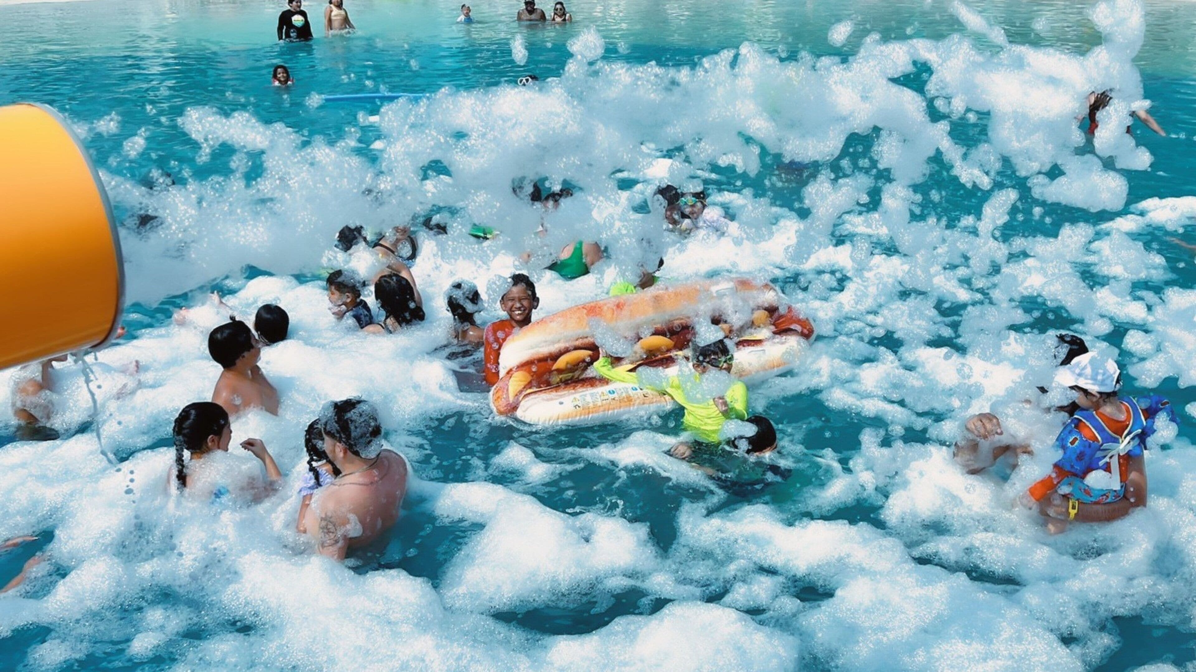 Un parc aquàtic ple d'atraccions inflables i persones gaudint de l'aigua.