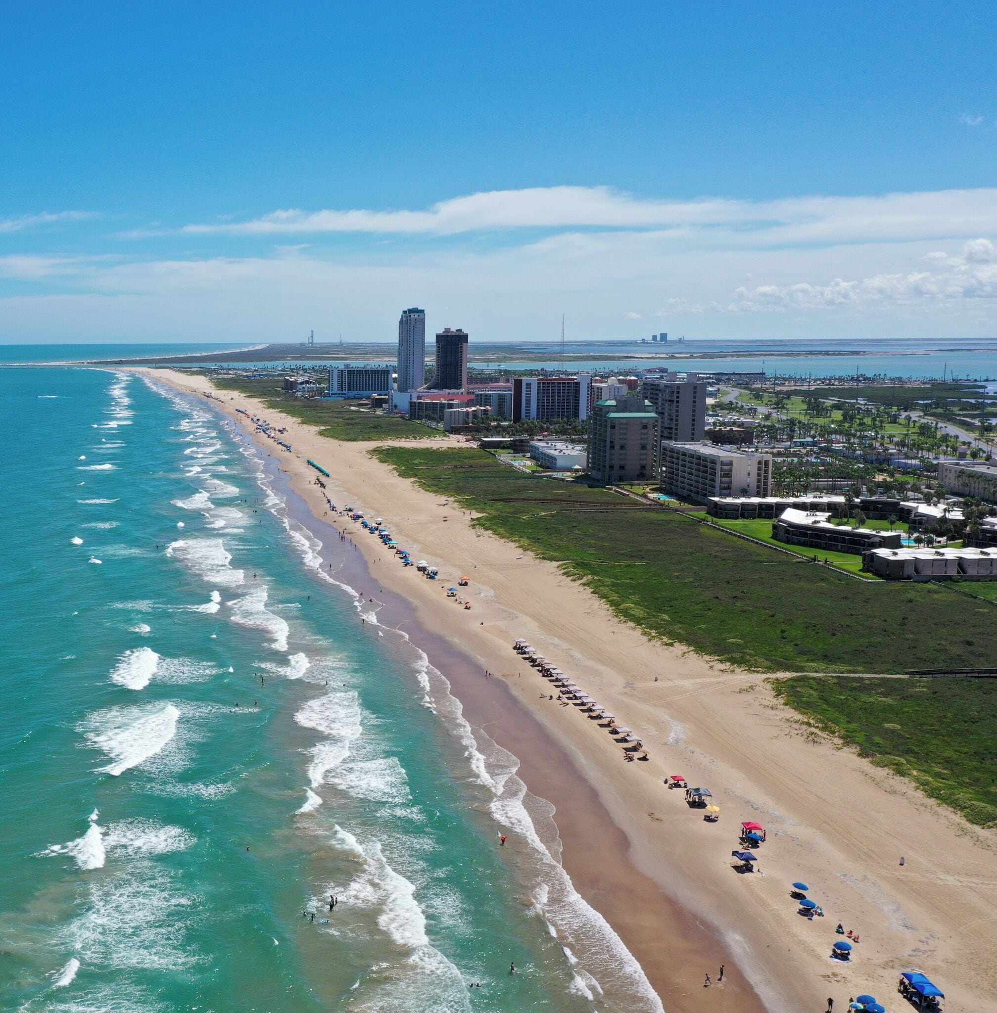 A coastal hotel with beachfront access, multiple buildings, and a sandy beach.