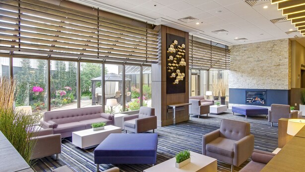 A spacious lobby with a fireplace, comfortable seating, and large windows offering a view of the outdoors. - Best Western Premier Calgary Plaza Hotel & Conference Centre (Calgary)