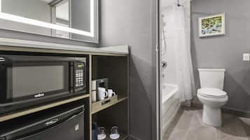 A modern bathroom with a built-in microwave, coffee maker, and storage shelves.