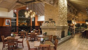 A restaurant with wooden tables and chairs, stone walls, and hanging light fixtures.