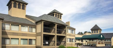 A multi-story hotel with balconies, a covered entrance, and a landscaped driveway.