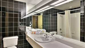 A modern bathroom with a white sink, large mirror, and black tiled walls.