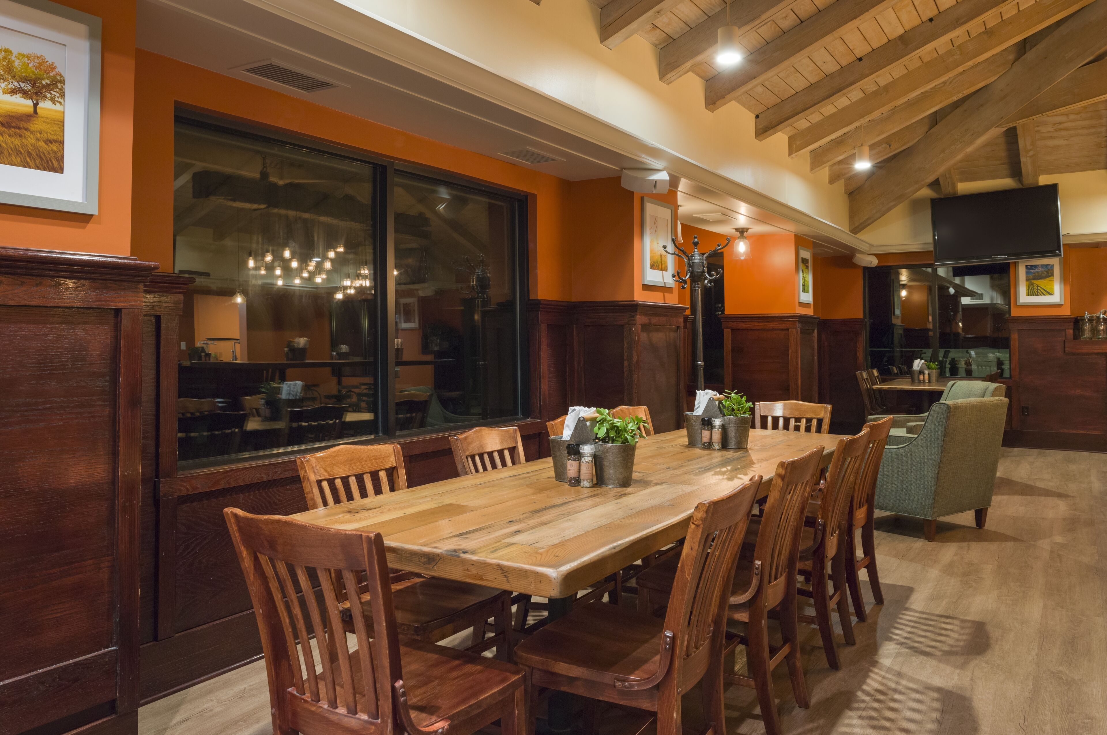 A restaurant with a wooden dining table, chairs, and a bar area.