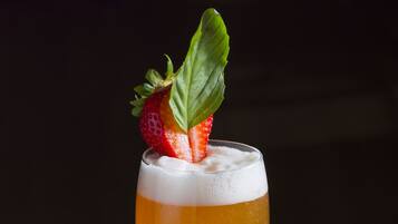 Un grand verre de bière, garni d’une fraise, posé sur un dessous de verre.