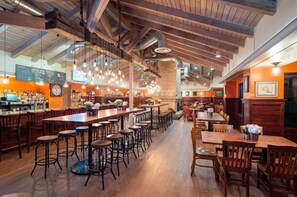 A spacious restaurant with high ceilings, exposed beams, and a variety of seating options including bar stools and tables. - Toftrees Golf Resort (State College)