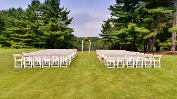 A grassy outdoor area with rows of white chairs arranged for an event.