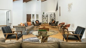 Amplia sala de estar con techo alto, una mesa de centro de vidrio, sofás de cuero y una mesa de centro de madera.