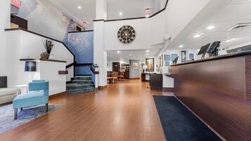 A hotel lobby with a staircase, a reception desk, and a large wall clock.