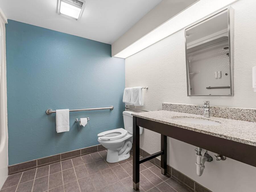 Een badkamer met een blauwe wand, een wit toilet en een wastafel met een spiegel erboven.