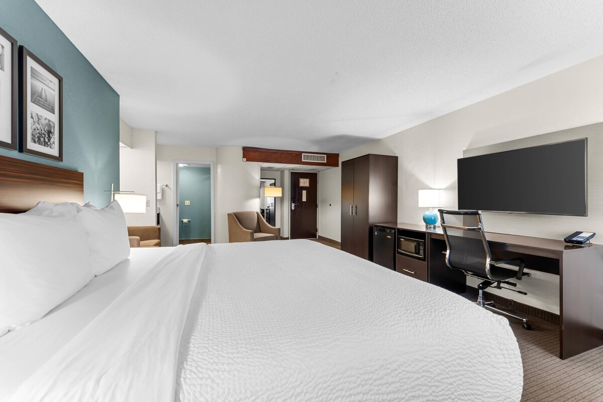 Habitación de hotel con una cama grande, un escritorio con una computadora, un televisor de pantalla plana y una silla.