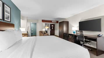 Habitación de hotel con una cama grande, un escritorio con una computadora, un televisor de pantalla plana y una silla.