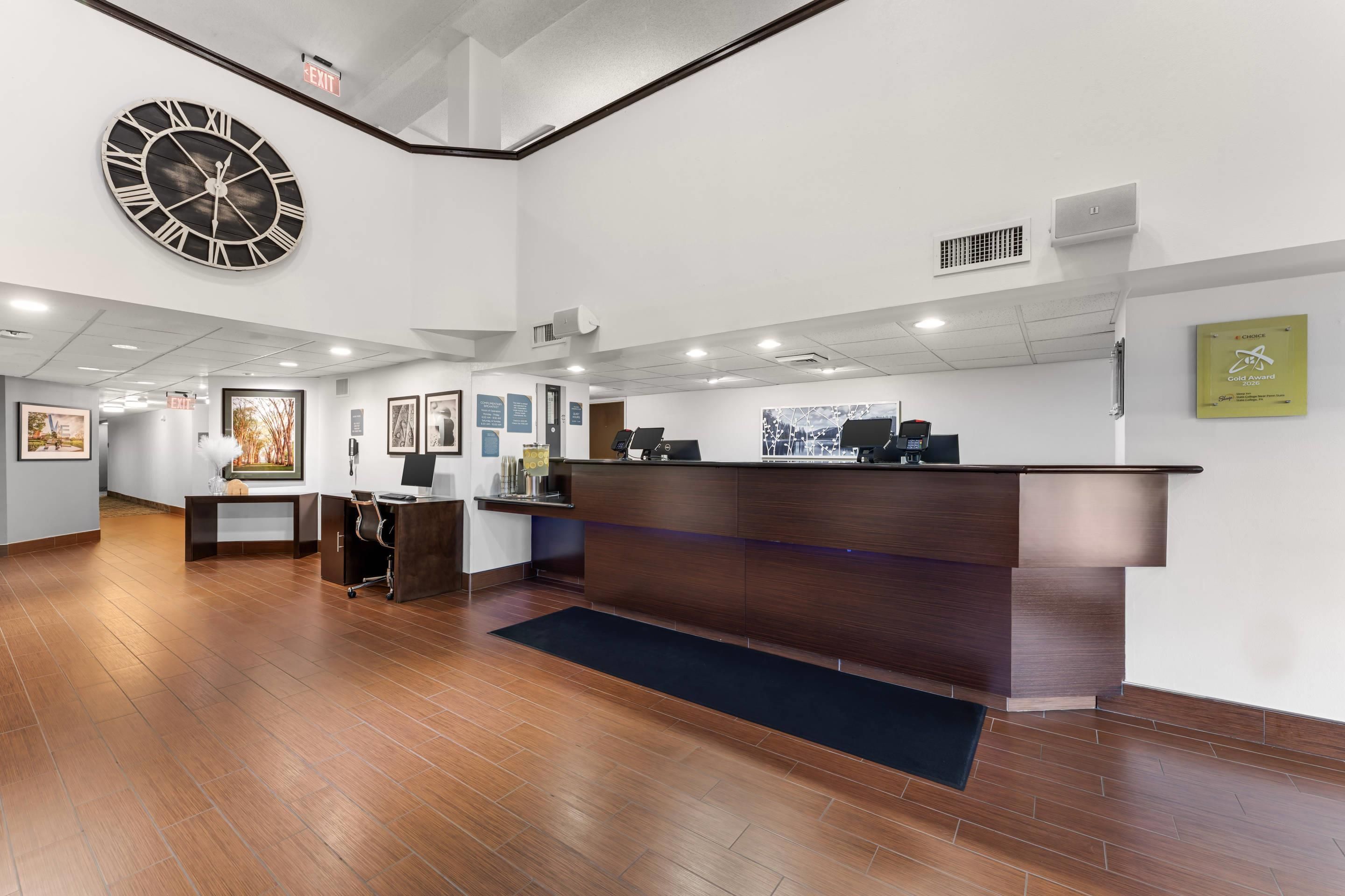 A reception area with a wooden floor, a reception desk, a large wall clock, and framed artwork.