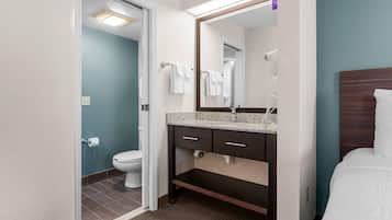Une salle de bain d’hôtel équipée de toilettes, d’un lavabo et d’un miroir.