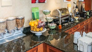 A breakfast buffet with various food options, including fruits, cereals, and waffles.