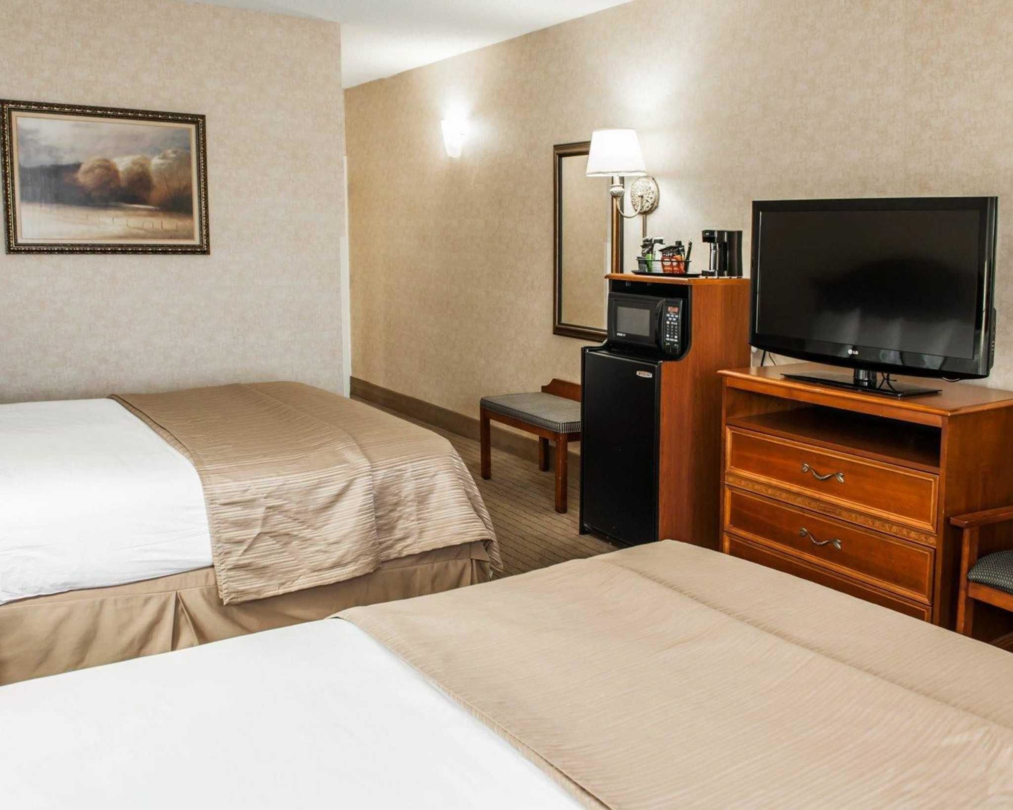 Une chambre d’hôtel avec deux lits, une télévision, un four à micro-ondes, une petite table et une chaise.