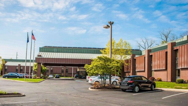 A parking lot with cars, a building with a green roof, and two flagpoles with flags.