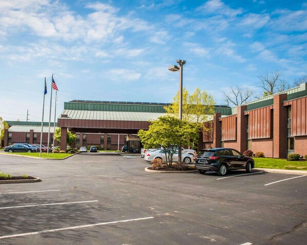 A parking lot with cars, a building with a green roof, and two flagpoles with flags.