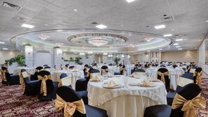 A banquet hall with round tables, black chairs with gold sashes, and a chandelier. - Best Western Plus Genetti Wilkes Barre (Wilkes-Barre)