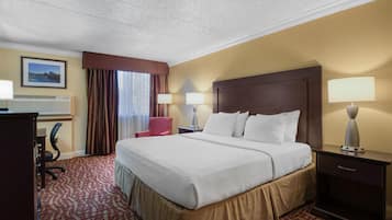 A hotel room with a large bed, two bedside lamps, a desk with a chair, and a framed picture on the wall.