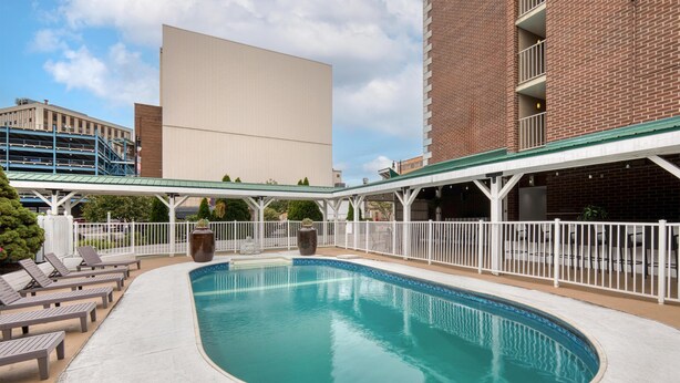 A swimming pool with lounge chairs and a covered walkway. - Best Western Plus Genetti Wilkes Barre (Wilkes-Barre)