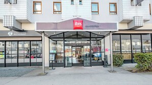 A modern hotel entrance with a glass facade, a red sign for ibis hotel, and a visible restaurant named "Le Trois Quatorze Restaurant" to the left. - ibis Marne La Vallée Champs (Champs-sur-Marne)