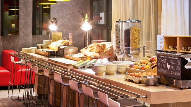 A breakfast bar with a coffee machine, bread, pastries, and a sign indicating food preparation times.
