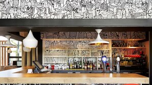 A bar area with a counter, bar stools, and shelves stocked with bottles.