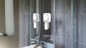 A modern bathroom with a large mirror, a white sink, and a glass-enclosed shower area. - ibis Marne La Vallée Champs (Champs-sur-Marne)