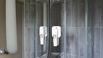 Un baño moderno con un espejo grande, un lavabo blanco y una zona de ducha con paredes de vidrio.