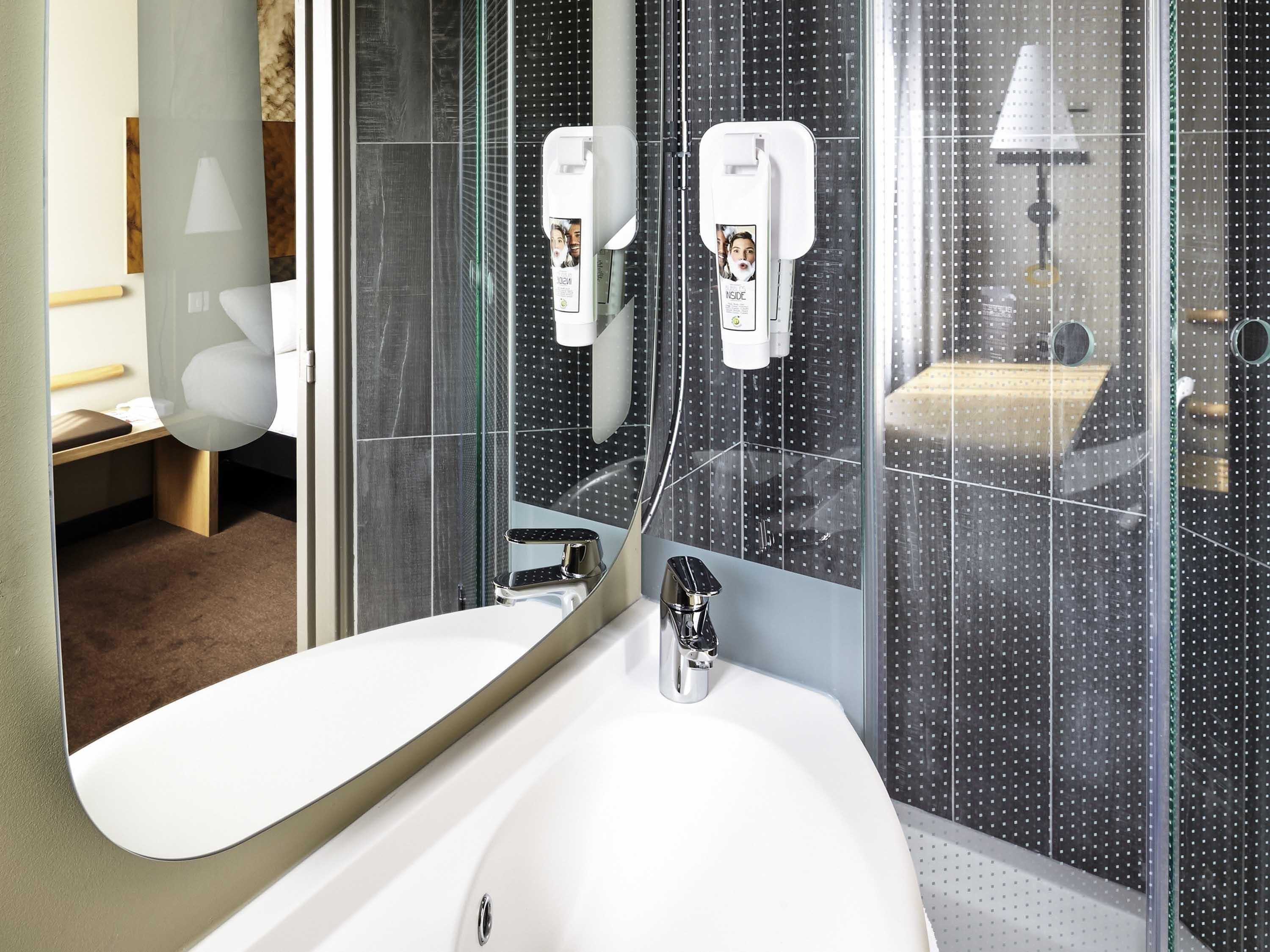 Une salle de bain moderne avec un grand lavabo, un miroir et un espace douche doté d’une porte en verre.
